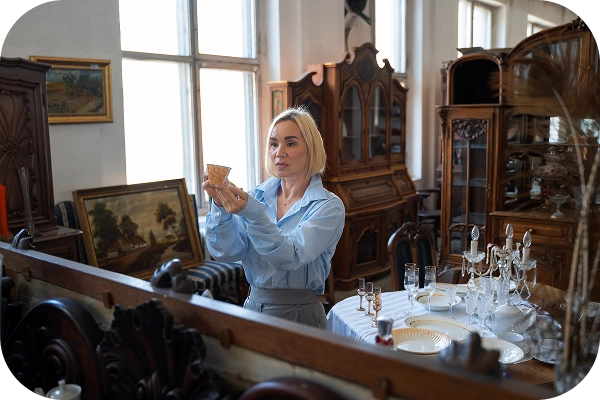 Kadın, klasik antika mağazasında antika mobilyalar ve vintage dekor ürünlerini inceliyor.
