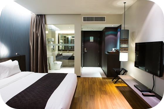 Modern konforlu otel odası iç mekanı, zarif aydınlatma, ahşap zemin ve çağdaş mobilyalarla.